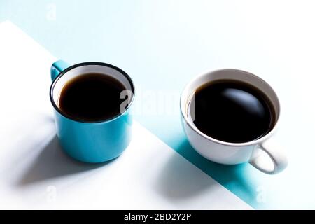 Flatlay top view of two coffee cups on white and blue paper background. Selective focus. Stock Photo