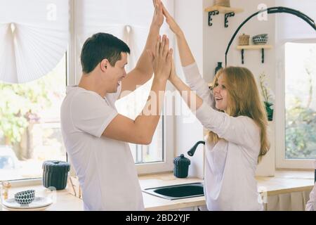 The guy and the girl clap their hands. The young couple have fun at home. Stock Photo