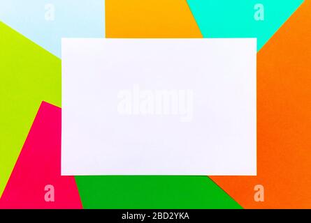 Flatlay of white blank sheet of paper mock up with a copy space on multicolored paper backgrounds. Top view, copy of space, selective focus. Stock Photo