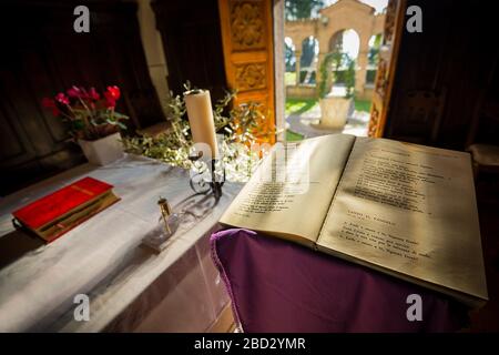 Wide angle view of a chapel adorned for mass, with a holy bible in the foreground, and a door open to a garden Stock Photo