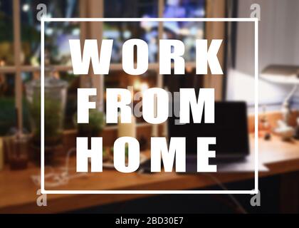 Work from home message concept. Laptop with flora decoration with lighting on wooden counter in house at night Stock Photo