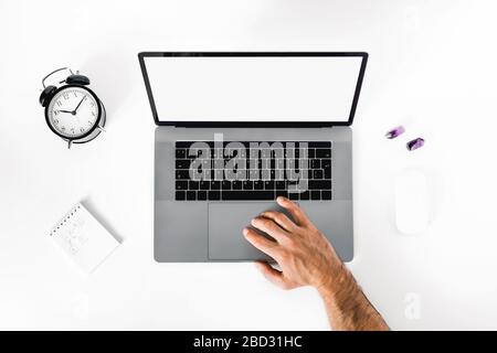 The man working at home on the remote. A black-and-white workplace with a laptop, alarm clock, notebook and men's hands. Stock Photo