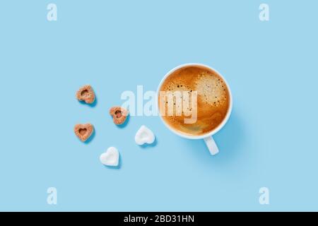 Morning cup of strong coffee with five pieces of sugar in the shape of hearts on blue background. Stock Photo