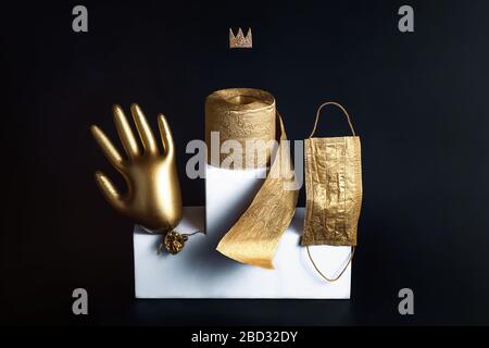 Gold glove, toilet paper and a mask on a white bollard. Concept on the theme of coronavirus trends. Black background. Stock Photo