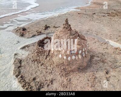 Sand castle on the beach with shells. Children's games at sea. Stock Photo