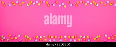 A lot of colored easter eggs, on a pink background. symbol of the spring holiday. Happy Easter card with copy space for text. Minimal style. Banner. Long format Stock Photo