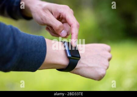 Man in nature using smartwatch app. Close-up hands Stock Photo