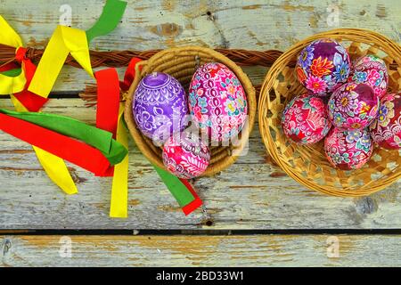 Still life with Easter eggs. Decorated Easter eggs lay in a wicker basket on a white wooden background, top view, copy space, copy space, place for Stock Photo