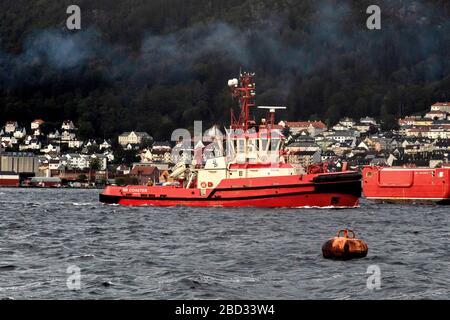 A grey and rainy day. Tug boat BB Coaster just completed assisting a cruise ship departing from the port of Bergen, Norway Stock Photo