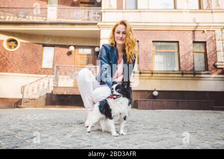 Theme walk with pet. Caucasian young woman and chihuahua dog on a leash in two of a european old house. dog chihuahua with her owner. theme is the Stock Photo