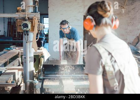 Team of carpenters planning wood using a machine Stock Photo