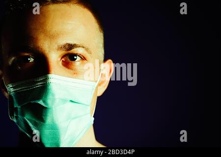 Caucasian man portrait in a medical gauze mask on dark blue background. Virus prevention concept Stock Photo