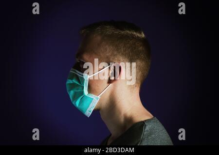 Caucasian man portrait in a medical gauze mask on dark blue background. Virus prevention concept Stock Photo