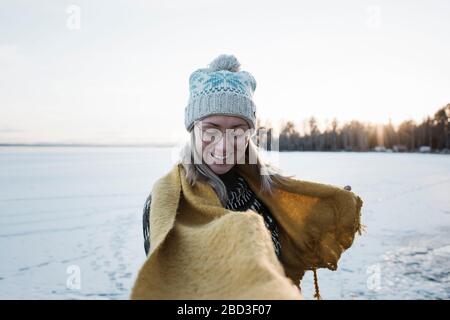 woman smiling whilst walking on a frozen lake in winter in Sweden Stock Photo