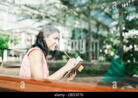 beautiful agronomical engineer taking notes sitting in the greenhouse Stock Photo