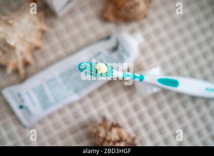 A toothbrush with toothpaste squeezed out on it against the background of a tube of toothpaste lying on the bathroom table. Stock Photo