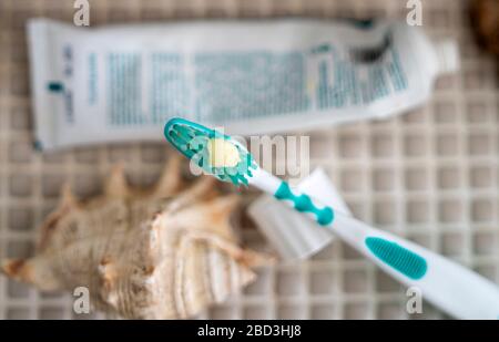 A toothbrush with toothpaste squeezed out on it against the background of a tube of toothpaste lying on the bathroom table. Stock Photo
