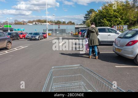 People queue in line observing social distancing waiting to enter a supermarket during the coronavirus pandemic. Stock Photo