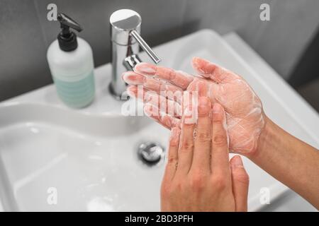 Washing hands rubbing soap in palm lathering up foam bubbles for corona virus COVID-19 prevention, hygiene to stop spreading coronavirus. Woman handwashing step at bathroom sink. Stock Photo