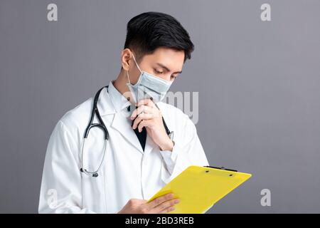 young Doctor Wear Medical Mask looking at exam report Stock Photo