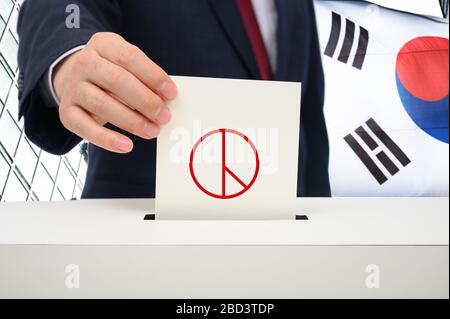 South Korea election concept. A man's hand with a ballot in a ballot box against the backdrop of a Korean flag Stock Photo