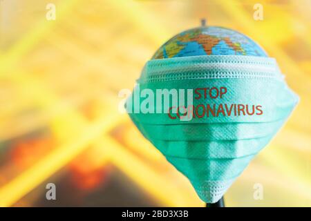 A world globe with a protective mask has a message to stop Coronavirus with blurred background and free space for text. Stock Photo