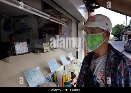 Antipolo City, Philippines - April 4, 2020: Man with improvised personal protective equipment and face mask buy rice from a store during the lockdown Stock Photo