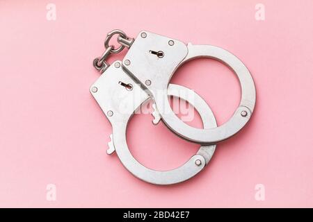 Closed handcuffs on a pink background, top view Stock Photo