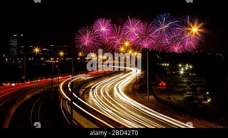 Fireworks exploding  at Skyworks on Australia Day in Perth. Also captures the car and train light trails on the freeway Stock Photo