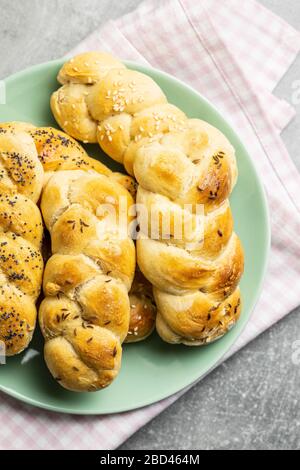 Tasty braided buns on green plate. Top view. Stock Photo