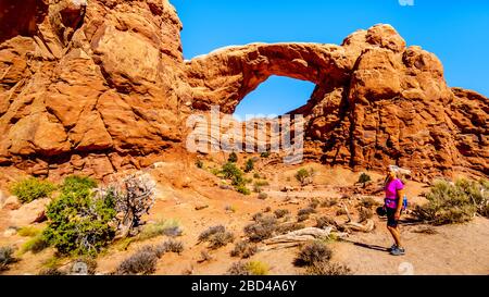 Woman on a Hiking Trail to the South Window Arch in the Windows Section in the desert landscape of Arches National Park, Utah, United States Stock Photo