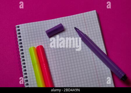 Multi colored felt tip pens and binder notepad at magenta background with copy space. Stock Photo