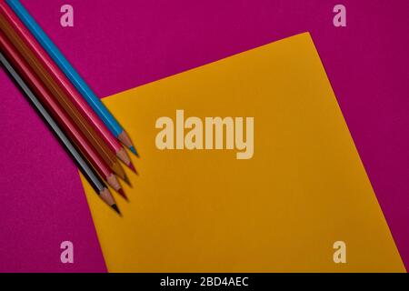 Multi colored crayons at yellow and magenta background with copy space. Stock Photo