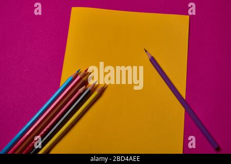 Multi colored crayons at yellow and magenta background with copy space. Stock Photo