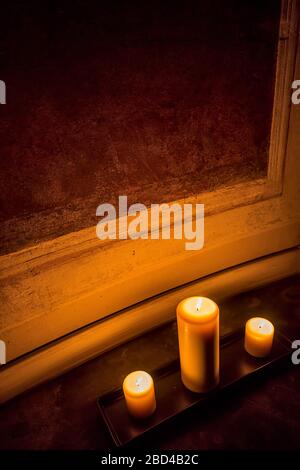 Close up three candles lying on a tray on the floor, close to an ancient decorated plaster wall Stock Photo