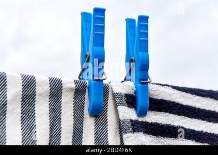 Dishcloths drying on clothesline. Closeup of two horizontal and vertical striped grey black white towels drying on a line with two blue clothespins. Stock Photo