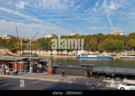 Visitors walking in front of moored River Cruise Barges on the River Seine, opposite the Museum of Modern Art. Stock Photo