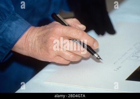 HM Queen Elizabeth II visits Rotherhithe Youth Hostel and signs a photo of herself, London England 1993. Photo shows the Queen's hand. Stock Photo