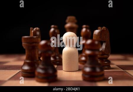 Wooden figures (businessman) standing confront of chess king and being in the chess circle. New business players are facing challenges. The management Stock Photo