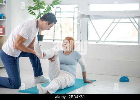 Nice pleasant woman having her leg supported Stock Photo