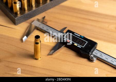 Production of cartridges for a rifle, reload. Measurement of the empty cartridges with a caliper. Side view Stock Photo