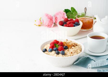 Oatmeal porridge with blueberry, raspberries, jam and nuts, side view, copy space, Stock Photo