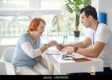 Pleasant aged woman taking a pen given by the doctor Stock Photo