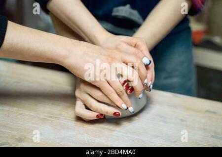 Woman making ceramic pottery, four hands close-up, focus on potters, palms with pottery, Stock Photo