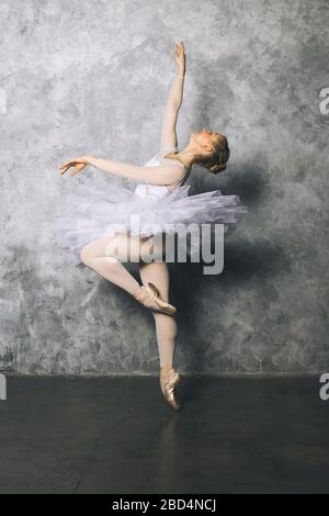 Pretty young ballerina dancer dancing classical ballet against old rustic wall Stock Photo