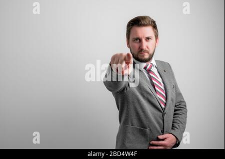 Portrait of business man wearing business clothes pointing camera isolated on grey background with copy space advertising area Stock Photo