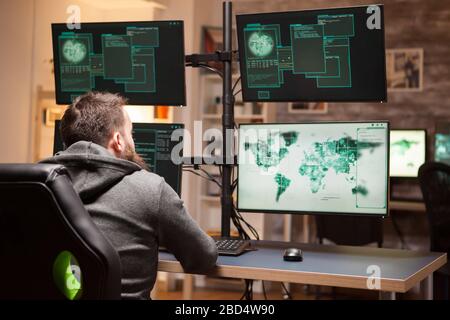 Rear view of dangerous hacker typing a malware to hack government server. Stock Photo
