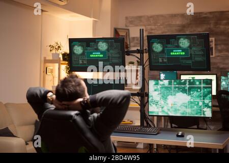 Happy hacker after a cyber attack using a dangerous malware. Access granted. Stock Photo
