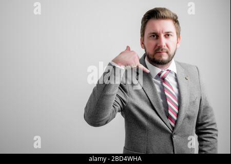 Portrait of business man wearing business clothes showing calling or contact gesture isolated on grey background with copy space advertising area Stock Photo