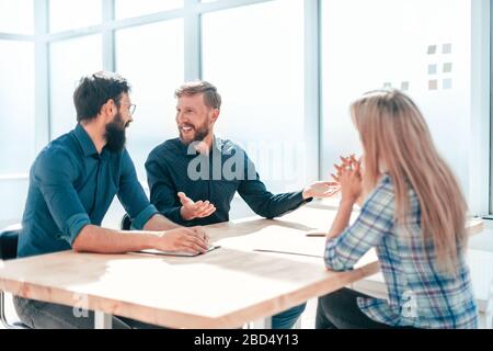 Women discuss documents sitting at table in office Stock Photo - Alamy